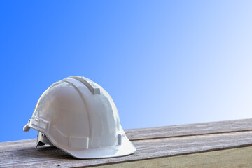 White safety helmet on wooden floor on blue tone for safety concept.