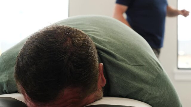 Back Of A Patient Being Cracked By A Chiropractor Close-up. Chiropractor massages the back of the patient.