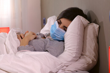 Woman with coronavirus sick lying in hospital bed with protection mask