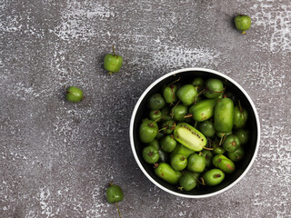 Mini kiwi baby fruit (actinidia arguta) in a bowl on a dark background. Top view, flat lay