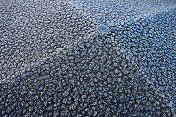 A fragment of a concrete fence covered with hoarfrost on a frost