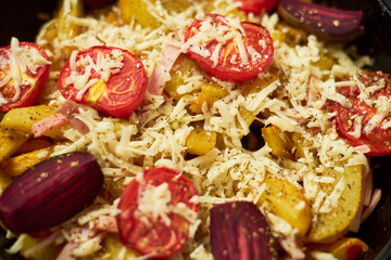 Baked potato with meat, tomatoes, beetroot in the oven. Sprinkled with cheese.