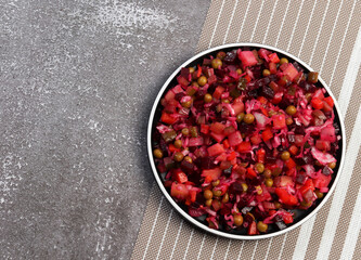 Traditional vinaigrette - salad of beetroot and vegetables on a round plate on a dark background. Top view, flat lay