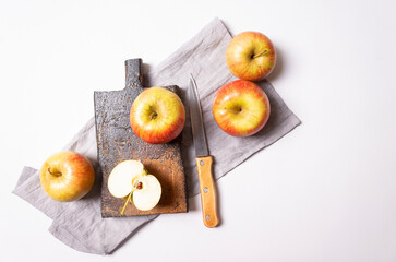 Apples, knife on a wooden board with a gray napkin. Top view on a white background.