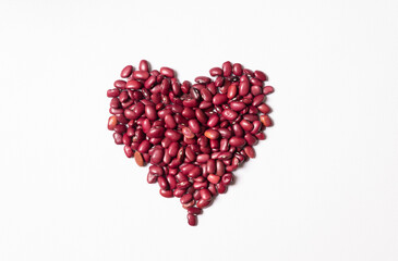 Fototapeta na wymiar Red beans, lined in the shape of a heart. On white background. Horizontal orientation.