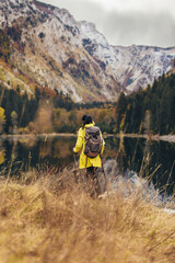 Woman with backpack and raincoat hiking Lifestyle adventure concept forest and lake on background active vacations into the wild