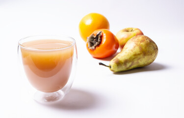 A glass of multifruit juice, fruits in the background. White background, horizontal orientation.