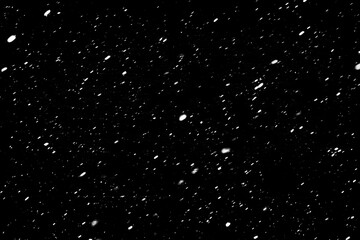 Falling snowflakes on a black background. The texture of the snow. Snowstorm. Element for the design. The bokeh effect.