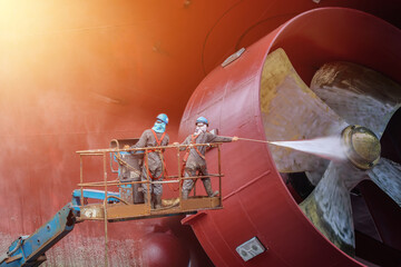 Cargo ship external wall cleaning shell on sherry picker car are doing these people at shipyard in Thailand.