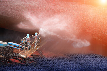 Worker in dry dock with water jet cleaners the bottom of the ship from sea vegetation and mussel colonies  during routine overhaul on outdated manual technology