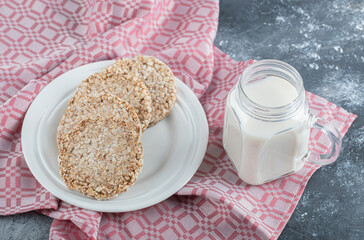 A white plate full of puffed rice bread with a jar of milk