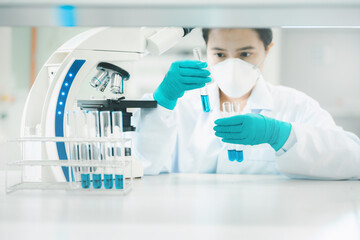 Doctor or scientist in laboratory holding liquid vaccines in medical research lab or science laboratory