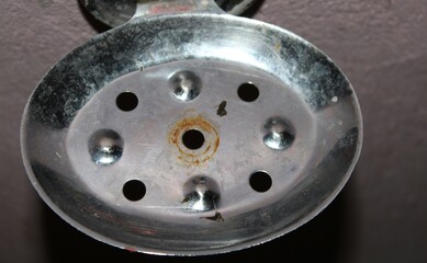 steel colour old soap stand in the bathroom and many hole in the stand.