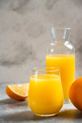 A glass cups of orange juice and slices of orange