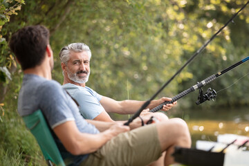 a mature father with his adult son outdoors fishing