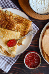 fresh homemade pancakes with red caviar and sour cream on a wooden background. Ukrainian and Russian national cuisine