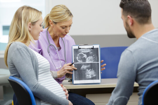 doctor showing couple the scan pictures of unborn baby