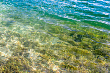Clear clear water of the lake with a turquoise hue on a sandy beach. The natural background
