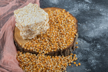 Tasty crispbread and raw corns on wood piece