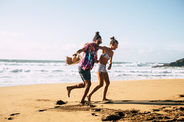 Young beautiful couple have fun and laugh at the beach in summer holiday vacation - people and travel lifestyle enjoy the sand and the sun playing together in outdoor leisure activity
