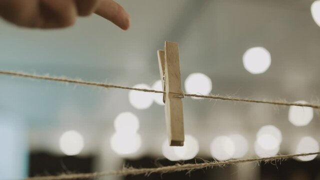 A wooden clothespin hangs and rotates on the twine, a wooden fastener is swinging by hand
