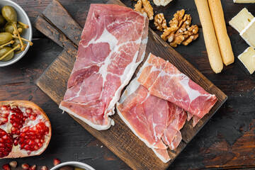 Traditional spanish jamon serrano ham, on dark wooden background, flat lay