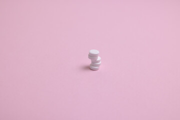 white pills on a pink background

