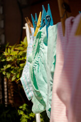 Baby clothes hanging on a clothesline drying in the sun. Portrait, selective focus. Pastel colours.