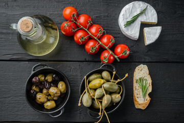 Mediterranean olives and capers, on black wooden table, top view