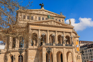 Historic building of the old opera house in Frankfurt in springtime with sunshine. Public square with trees in the center of the city with commercial and office buildings in the background