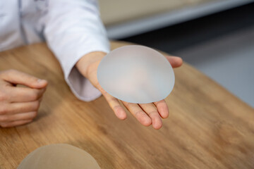 Silicone breast implant in doctors hands. Selective focus on plastic surgeon`s hand with brest implant.