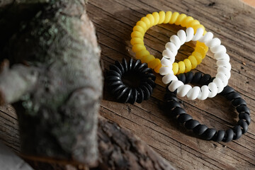 Fashionable and modern elastic hair springs. Different colors of stretching hand bracelets on wooden background, stand