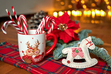 New Year's Cup of hot drink in front of the Christmas tree on a red tablecloth stands near the New Year's decorations. Winter holidays concept. Cozy magical atmosphere in the house.