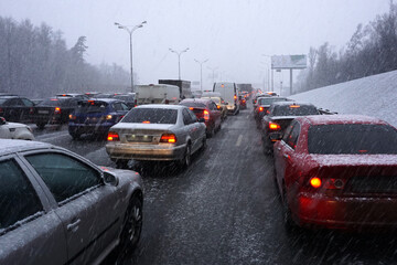 Cars got stuck in a traffic jam on a multi-lane highway due to snowfall.