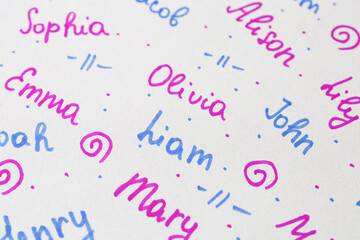 Different baby names written on paper, above view