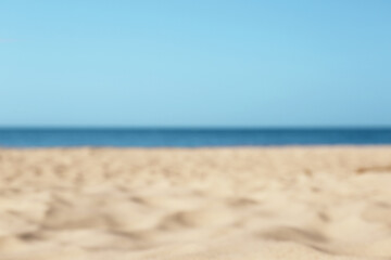 Fototapeta na wymiar Blurred view of beautiful sandy beach and sea on sunny day. Summer vacation