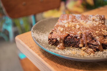Plate with slice of tasty homemade chocolate cake on wooden table. Homemade brownie cake