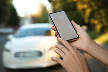 Woman ordering taxi with smartphone on city street, closeup