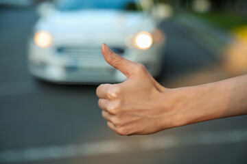 Woman hitchhiking taxi on city street, closeup