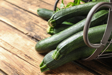 Basket with green zucchinis on wooden table, closeup