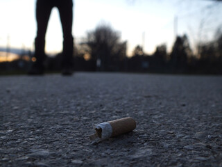 Zigarette liegt am boden und im hintergrund ist eine person 