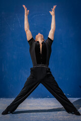 Male latin dancer in front of a dark blue wall