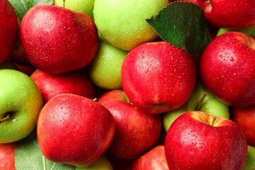 Many different wet apples with leaves as background, closeup