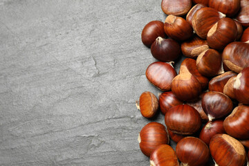 Fresh sweet edible chestnuts on black slate table, flat lay. Space for text