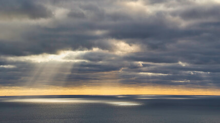 Sunset sky with clouds over ocean with sun rays dramatic landscape