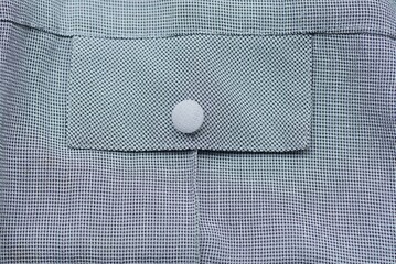 one small white button on gray fabric with a pocket