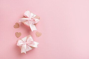 Gift boxes with pink ribbon and hearts on pastel pink background. Valentines day composition with free space. Top view, flat lay.