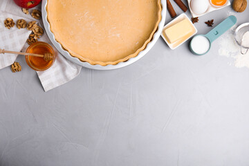 Raw dough and traditional English apple pie ingredients on light grey table, flat lay. Space for...