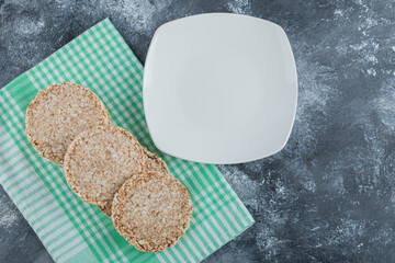 An empty white plate with crispy rice bread on a marble background