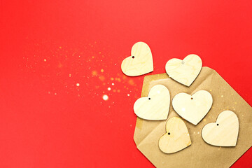 Wooden hearts spill out of an open envelope on a red background. Valentine's Day, love letter, declaration of love, acquaintance. Copy space, mock up